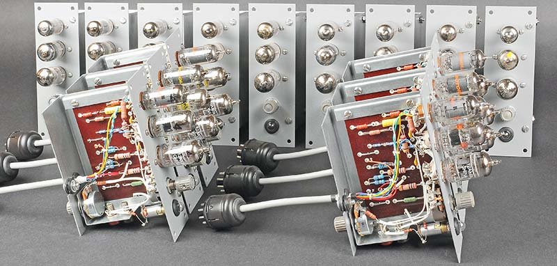 Nine of the fifteen ES-201 op-amp modules removed from the ES-400, arranged to show both the tube-top view and the component side of the phenolic PCB. The dense wiring, axial capacitors, and three tube sockets per module are visible.